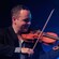 Hombres se miran mientras tocan violines
